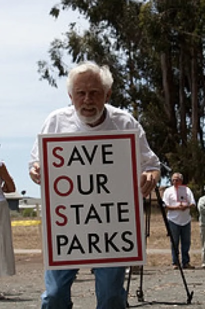man holding sign saying 'save our state parks'